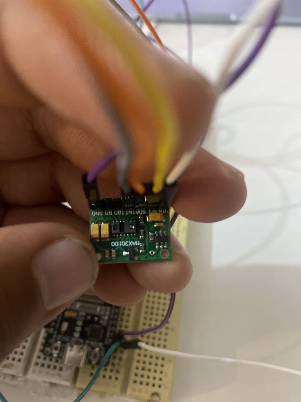 The MAX30100 pulse and blood-oxygen sensor breakout board held between two fingers.
