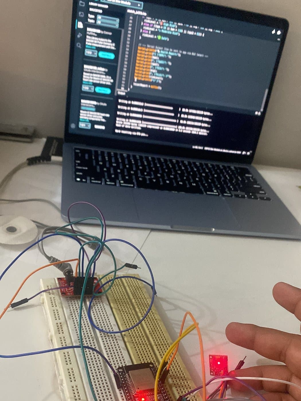 The full setup taking a live reading — laptop showing serial output, ESP32 on the breadboard, and the pulse sensor lit against a fingertip.